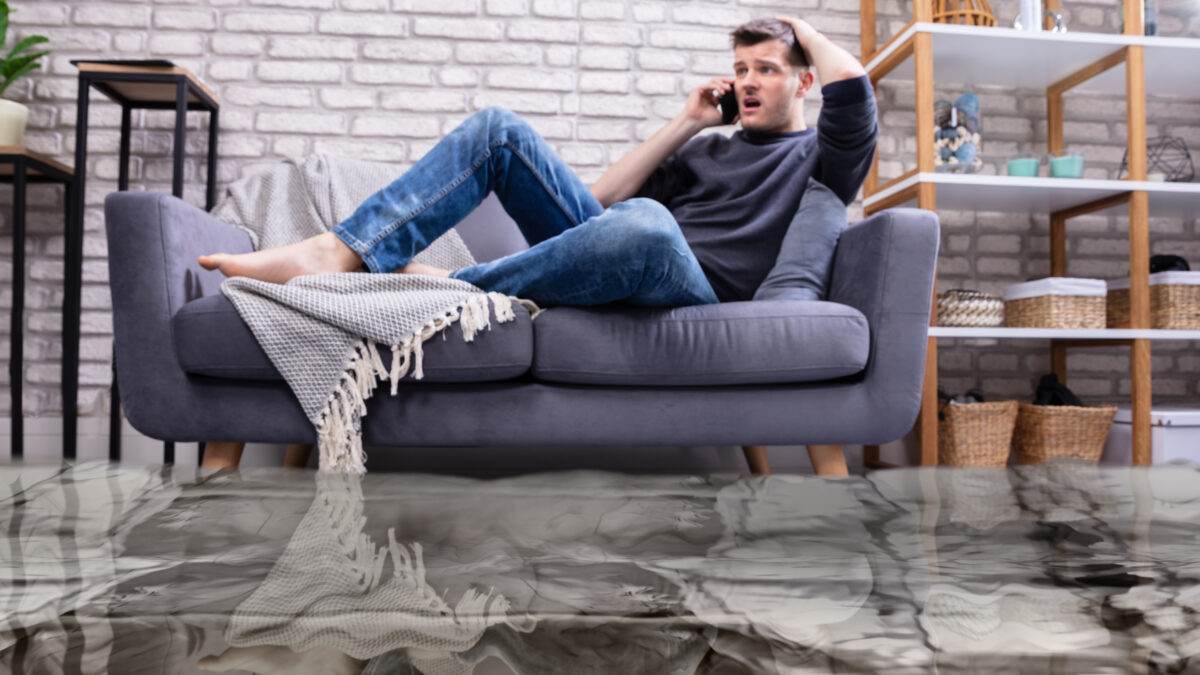 Man Sitting On Sofa Calling To Plumber