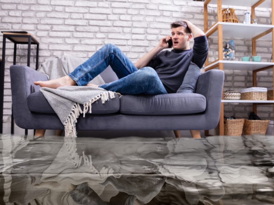 Man Sitting On Sofa Calling To Plumber